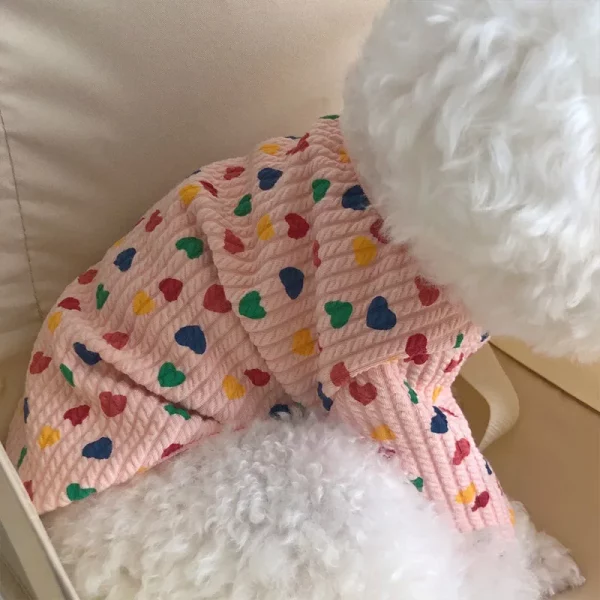 Dog wearing pink heart print dog clothes, side view showing fit