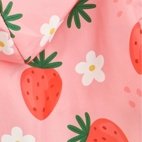 Detail shot of the closure mechanism on the pink strawberry dog raincoat, likely Velcro or snaps.