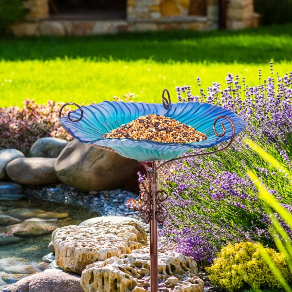 The complete glass bird bath assembled, showing the bowl and the 4-prong stake inserted into grass.