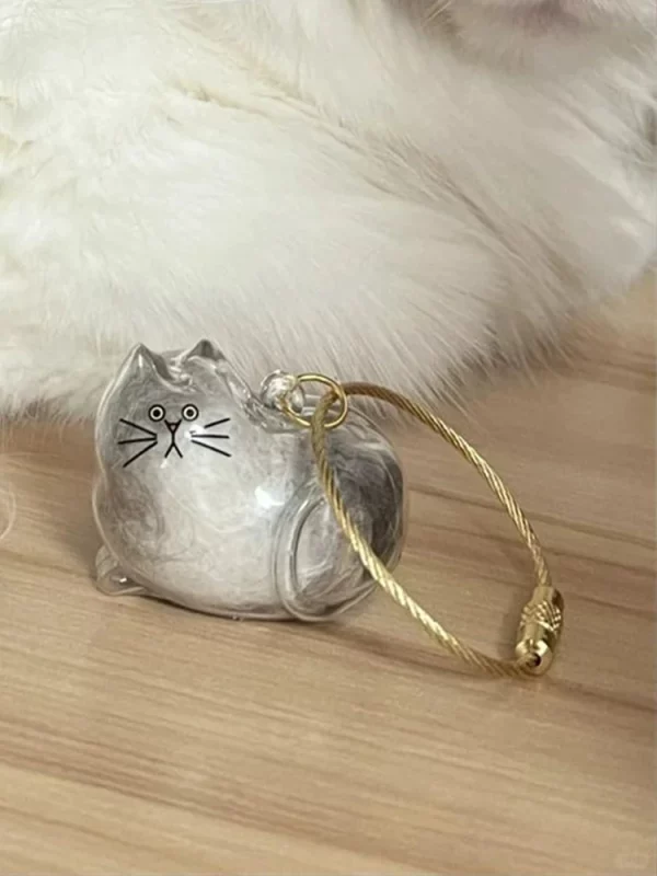Cat hair storage capsule keychain attached to a handbag, as a stylish accessory.