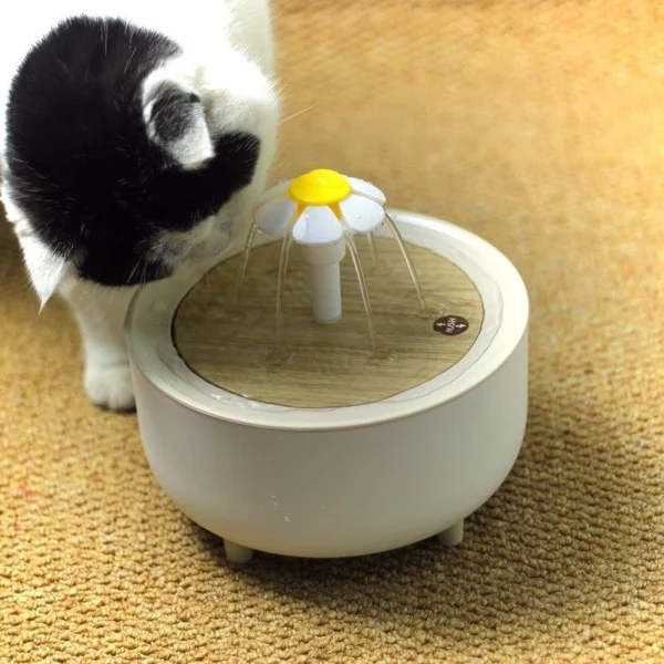 A cat drinking from the automatic water fountain.